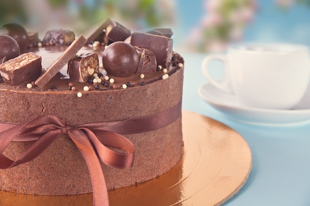 Chocolate cake with candy and ribbon on a blue table