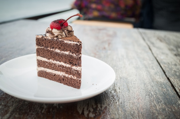 Chocolate cake with cherry topping in cozy outdoor cafe