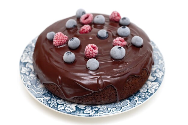 Chocolate cake with frozen berries on plate on white background