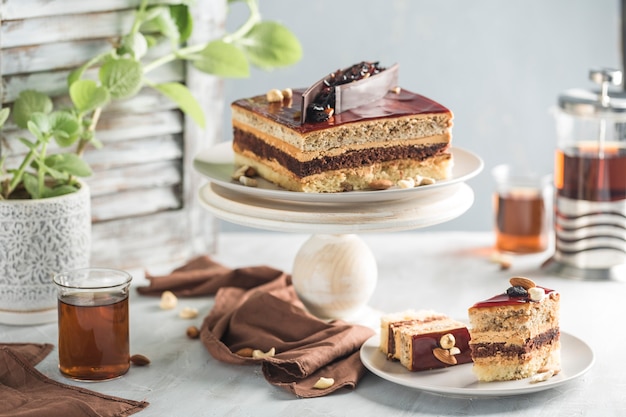 Шоколадный торт с орехами на деревянной подставке с нарезанными кусочками на тарелке с помощью френч-пресса