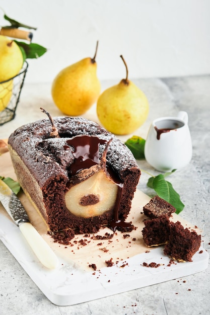 Chocolate cake with pears baked inside chocolate pear cake or\
dark chocolate bundt cake with pear on light gray table at home\
home cooking and baking recipes concept selective focus