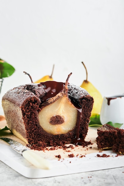 Chocolate cake with pears baked inside chocolate pear cake or\
dark chocolate bundt cake with pear on light gray table at home\
home cooking and baking recipes concept selective focus