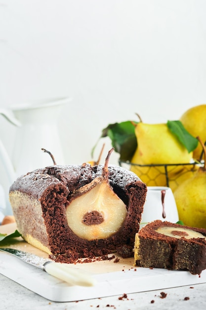 Chocolate cake with pears baked inside chocolate pear cake or\
dark chocolate bundt cake with pear on light gray table at home\
home cooking and baking recipes concept selective focus