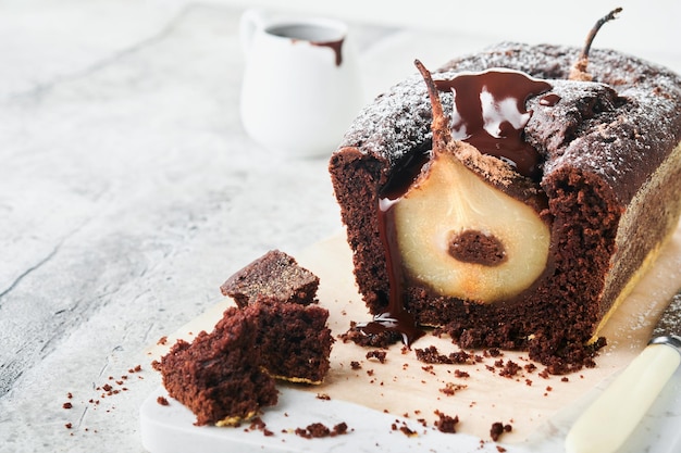 Chocolate cake with pears baked inside chocolate pear cake or\
dark chocolate bundt cake with pear on light gray table at home\
home cooking and baking recipes concept selective focus