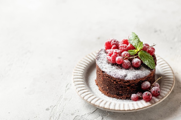 Chocolate cake with red berries mint and snowy powdered sugar\
on textured background with copy space