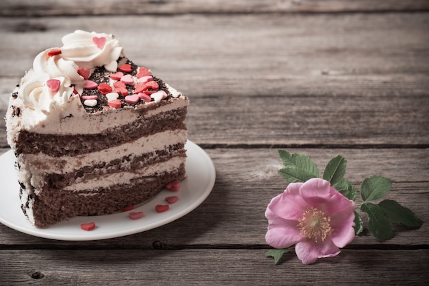 Chocolate cake with rose on old wooden background