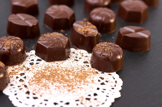 Шоколадные конфеты на черной поверхности, какао-порошок. темное фото, настроение.