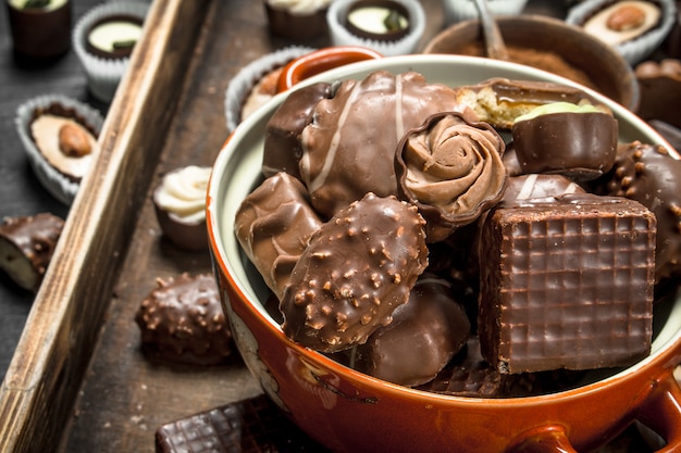 Шоколадные конфеты в миске. На деревянном подносе