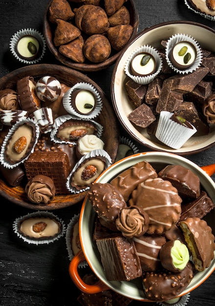 Chocolate candies in a bowls. On the black chalkboard.