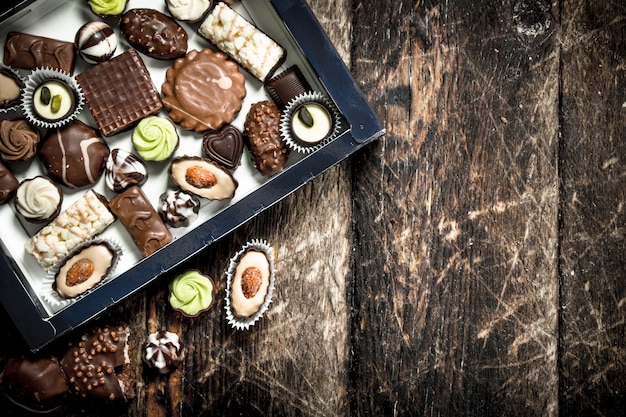 Chocolate candies in a box. On a wooden background.