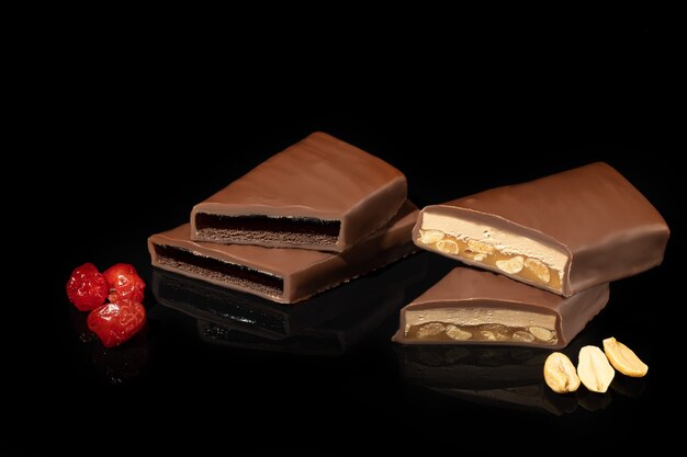 Chocolate candies on a dark surface with reflection. Filling of nuts and fruits. Copy space.