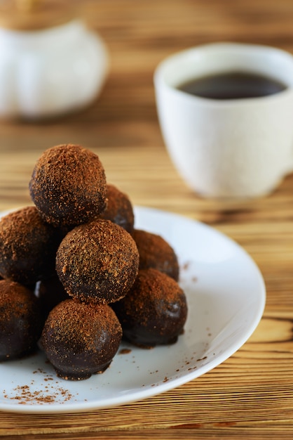 Chocolate candies in the form of a pyramid with a cup of coffee on a wooden table.