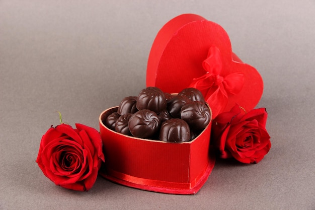 Chocolate candies in gift box, on grey background