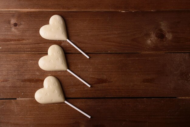 Chocolate candies in shape of hearts on wooden background