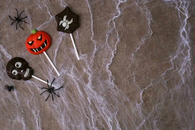 Chocolate candies in the shape of skull, Jack pumpkin and spider on background of cobwebs. Halloween concept