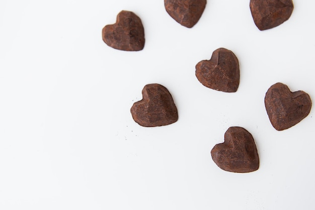 Шоколадные конфеты с трюфелем в виде сердца на белом фоне, крупным планом. Место для надписи.
