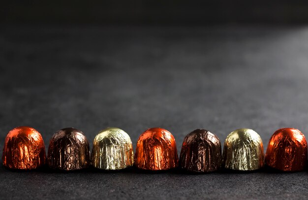 Chocolate candies wrapped in multicolored foil on black surface