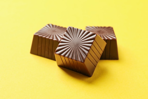 Chocolate candies on yellow background