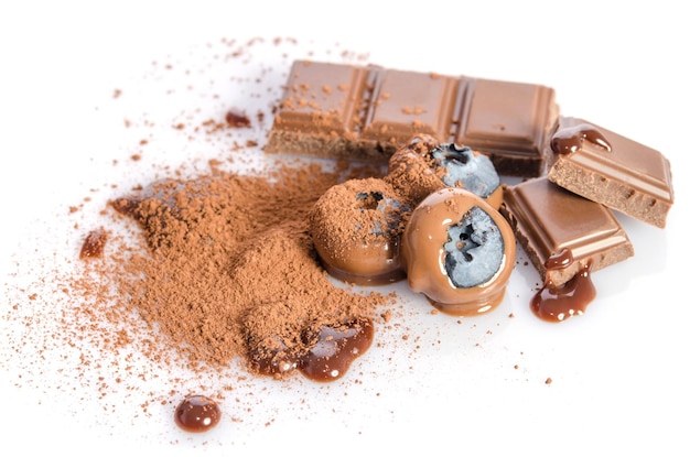 Caramelle al cioccolato e polvere di cacao con mirtillo isolato su bianco