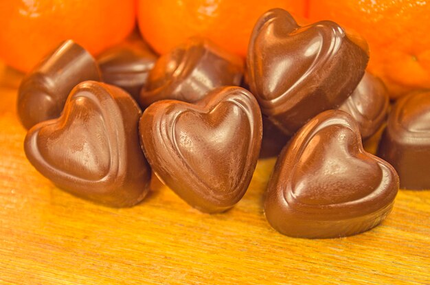 Chocolate candy and orange on a wooden table