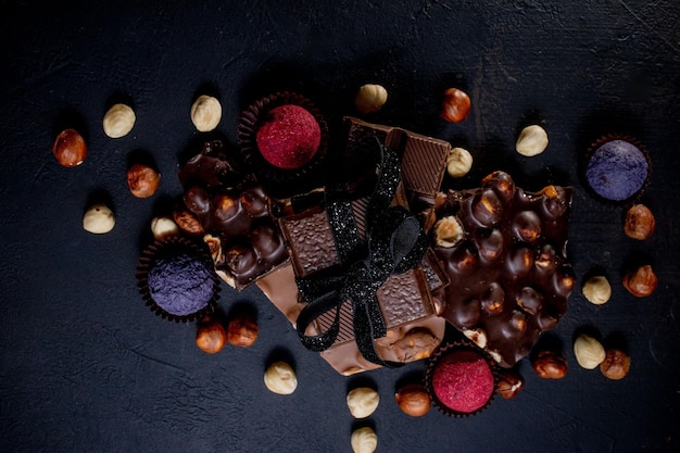 Chocolate candy truffle with chocolate pieces and flying cocoa powder on a dark background