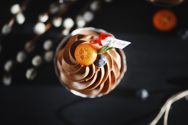 Chocolate capcake on a dark background decorated with kumquat and blueberries