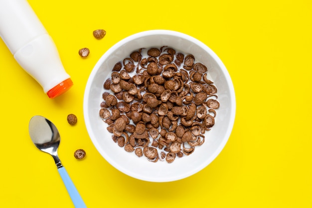 Chocolate cereal with milk on yellow surface. 