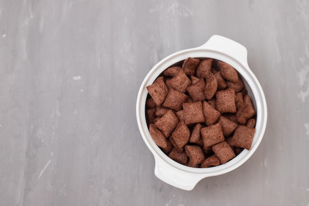 Chocolate cereals in small white bowl on ceramic