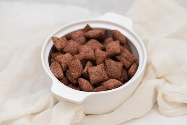 Chocolate cereals in small white bowl on ceramic