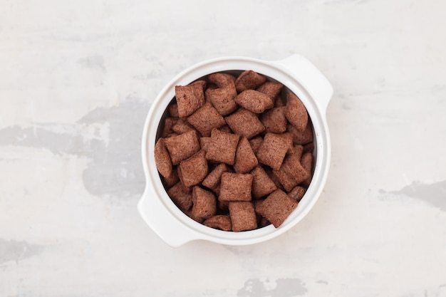 Chocolate cereals in small white bowl on ceramic