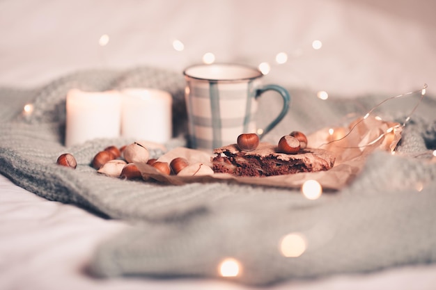 Chocolate charlotte pie with nuts and cup of tea over burning candles close up. Good morning. Tasty breakfast in bed.