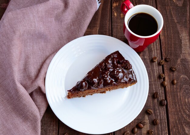 Torta al cioccolato e ciliegie. un pezzo su un primo piano piatto bianco. una tazza di caffè. la vista dall'alto.