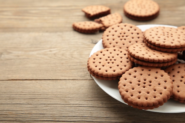 灰色の木製の背景の白いプレートにチョコレートチップクッキー。上面図。