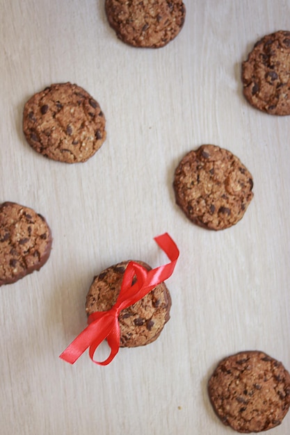 Photo chocolate chip cookies arranged symmetrically, one cookie tied with a red ribbon