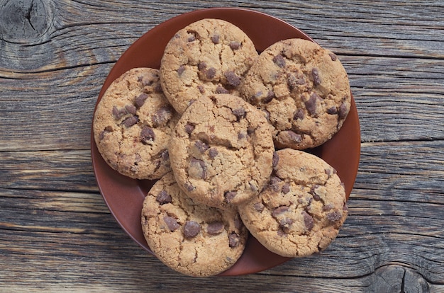 Chocolate chip cookies on a brown plate on old wooden table