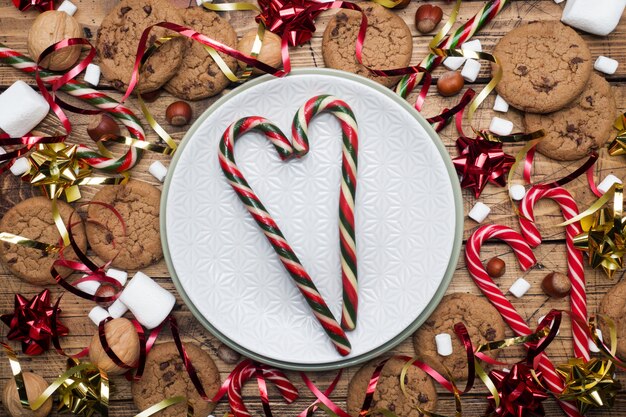 Chocolate chip cookies Christmas canes caramel red gold scenery and marshmallow on wooden  empty plate. copyspace Frame.