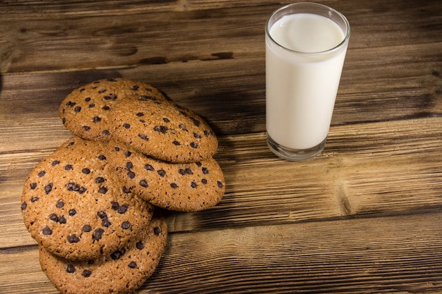 Chocolate chip cookies and glass of milk on wooden table