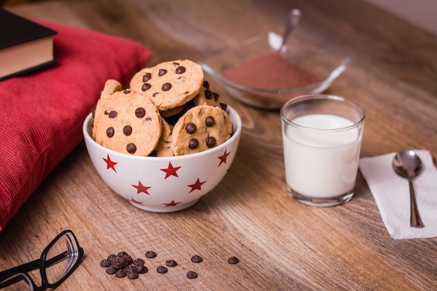 Chocolate chip cookies and milk on wood background