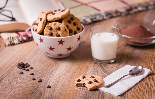 Chocolate chip cookies and milk on wood background