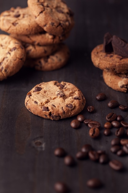 Biscotti al cioccolato sul vecchio tavolo in legno con chicchi di caffè. spuntino fatto in casa.