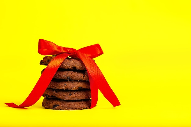 Chocolate chip cookies tied with a red ribbon on a yellow background