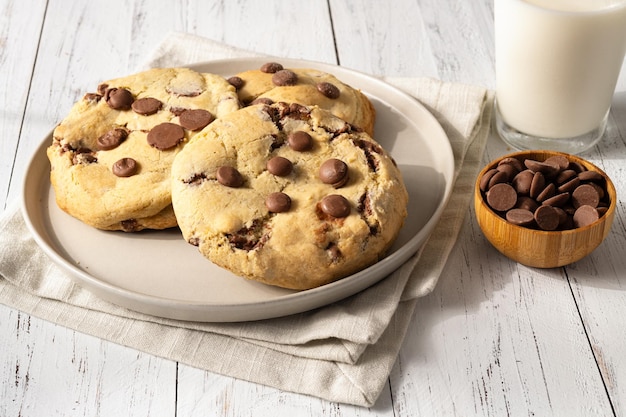 Chocolate chip cookies over white wooden table with milk