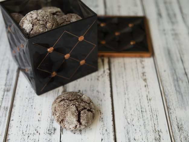 Biscotti con gocce di cioccolato, crepe, scatola vintage nero con biscotti su sfondo bianco.