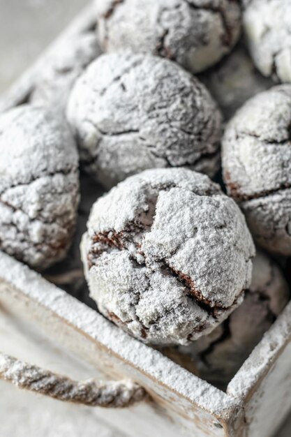 Foto biscotti al cioccolato incrinati da vicino scatola rustica in legno con biscotti al cioccolato appena sfornati in zucchero a velo