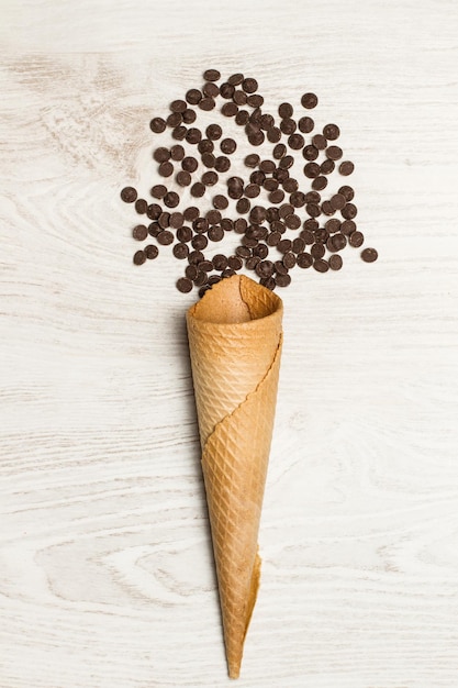 Chocolate chips in a wafer cone and on a white wooden table