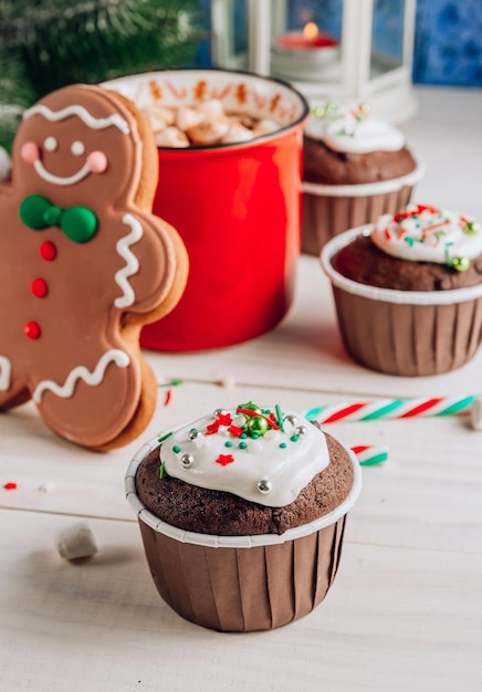 Photo chocolate christmas cupcake with colored sugar topping and red cup of coffee on whithe wooden background selective focus