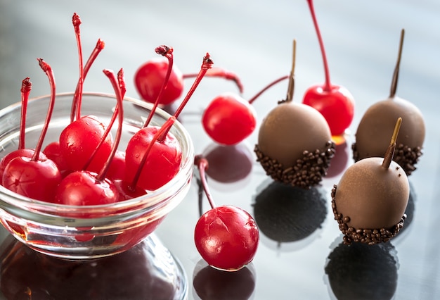 Photo chocolate and cocktail cherries on glass table