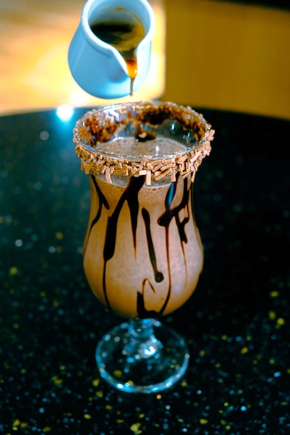 A chocolate cocktail with a chocolate sauce being poured over a glass.