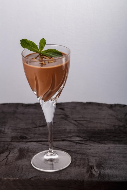 Фото Шоколадный коктейль с орехами и мятой в стакане на черном фоне вертикального фото