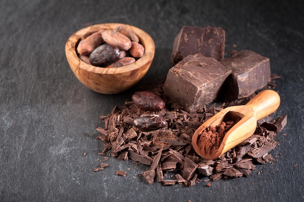 Chocolate cocoa beans and cocoa powder on a stone background